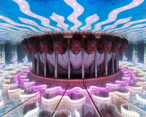 A young visitor is reflected inside the Infinity Boxes exhibit