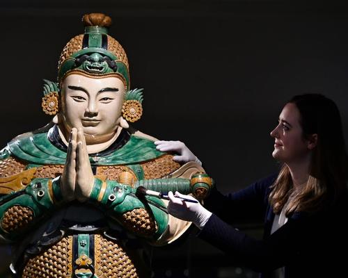 A museum conservator cleans a statue of Weituo, the leading guardian of Buddhist faith and teachings