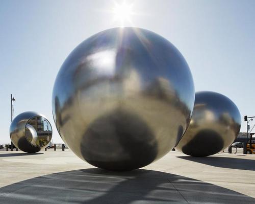The artwork consists of five polished, hydroformed steel orbs
