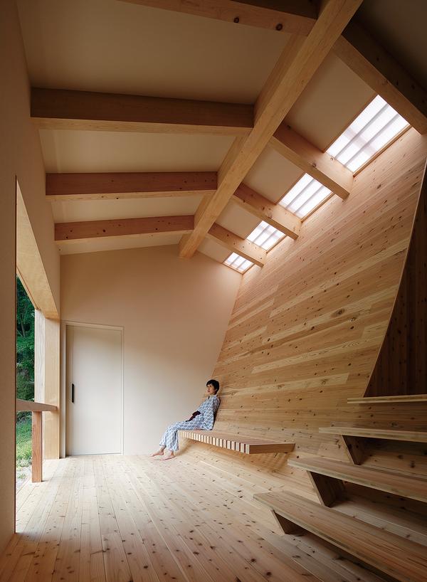 The curved cedar wall separates a relaxation area and a submerged spring water bath 