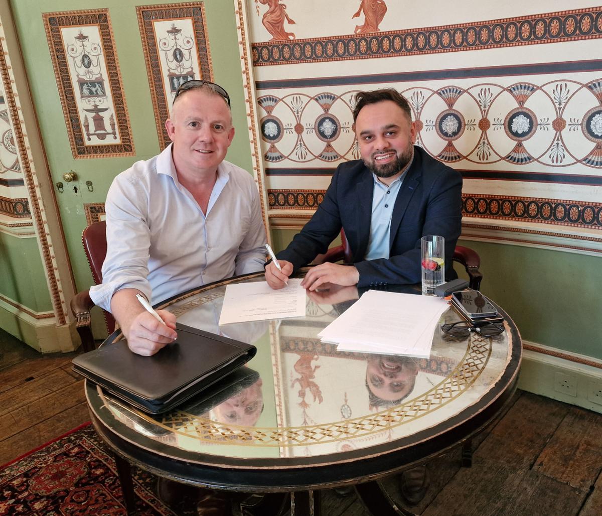 Elliot Walker, co-founder of The Massage Company (L), and Adeel Ashgar, head of brands at Franchise& (R), signing the new Scottish deal / 