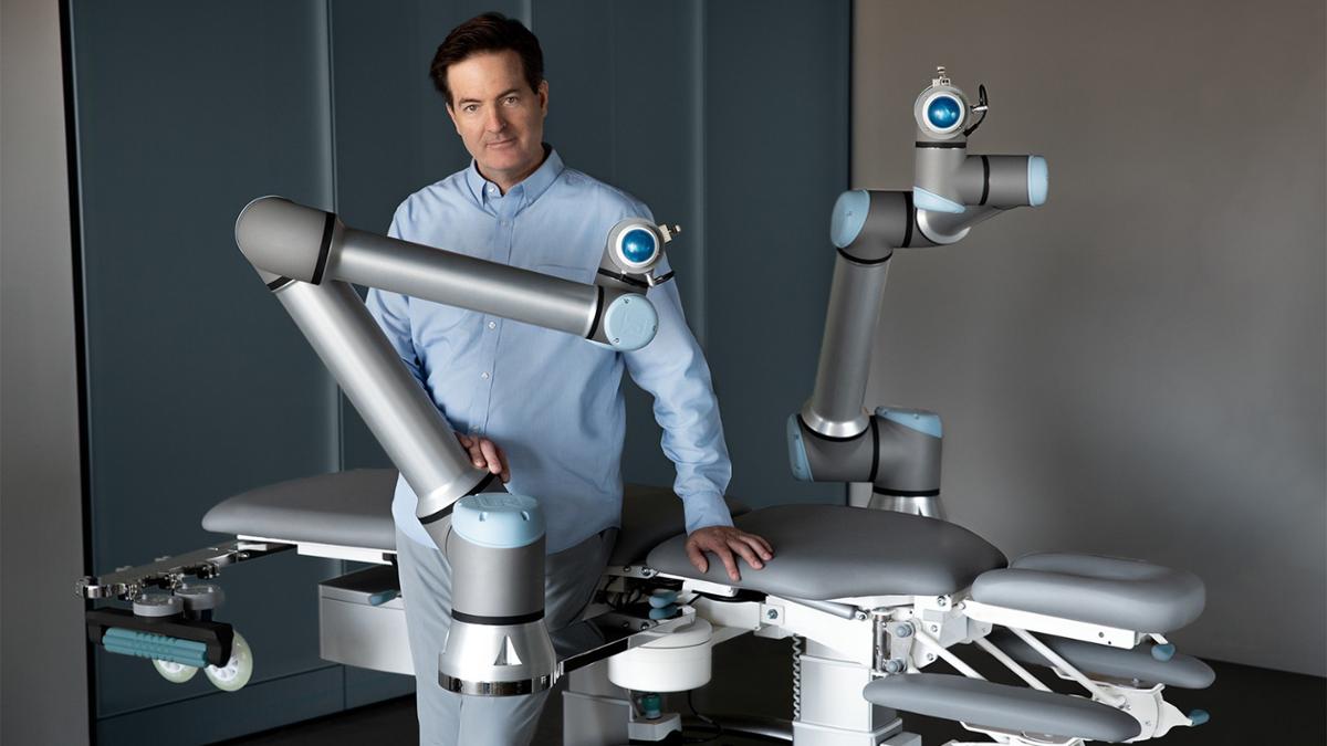 Christian Mackin pictured with Massage Robotics life-sized AI-powered massage robot; Alex / Massage Robotics