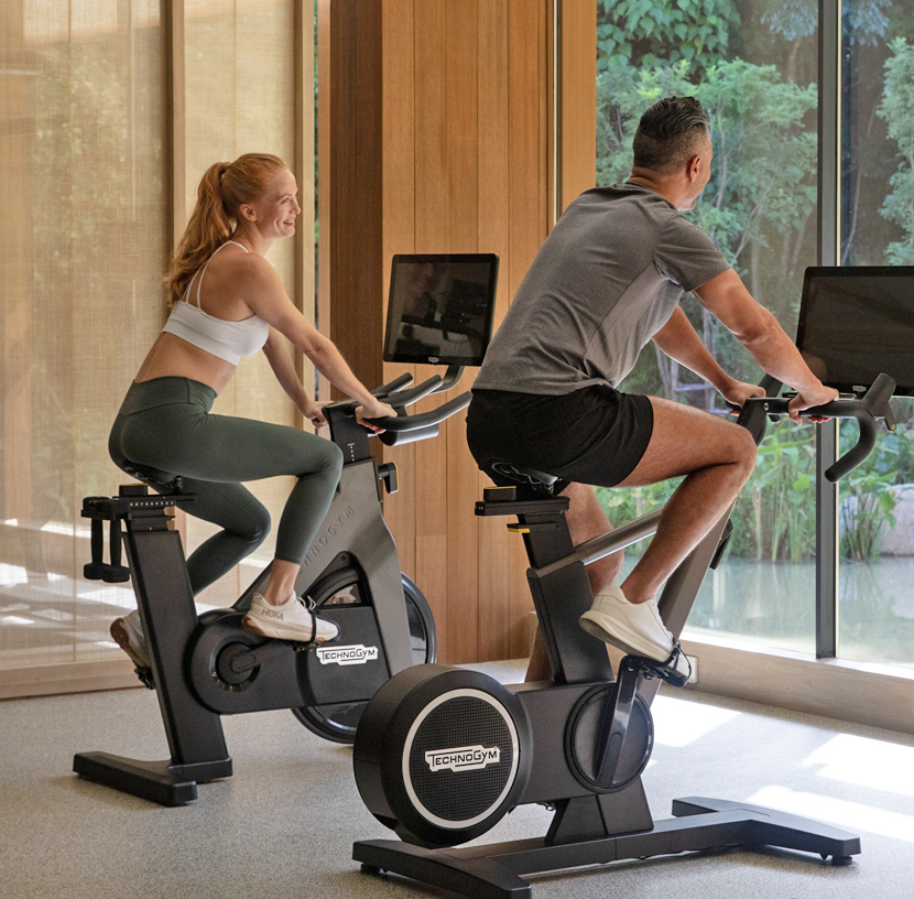 Man and woman on Technogym exercise bikes in gym