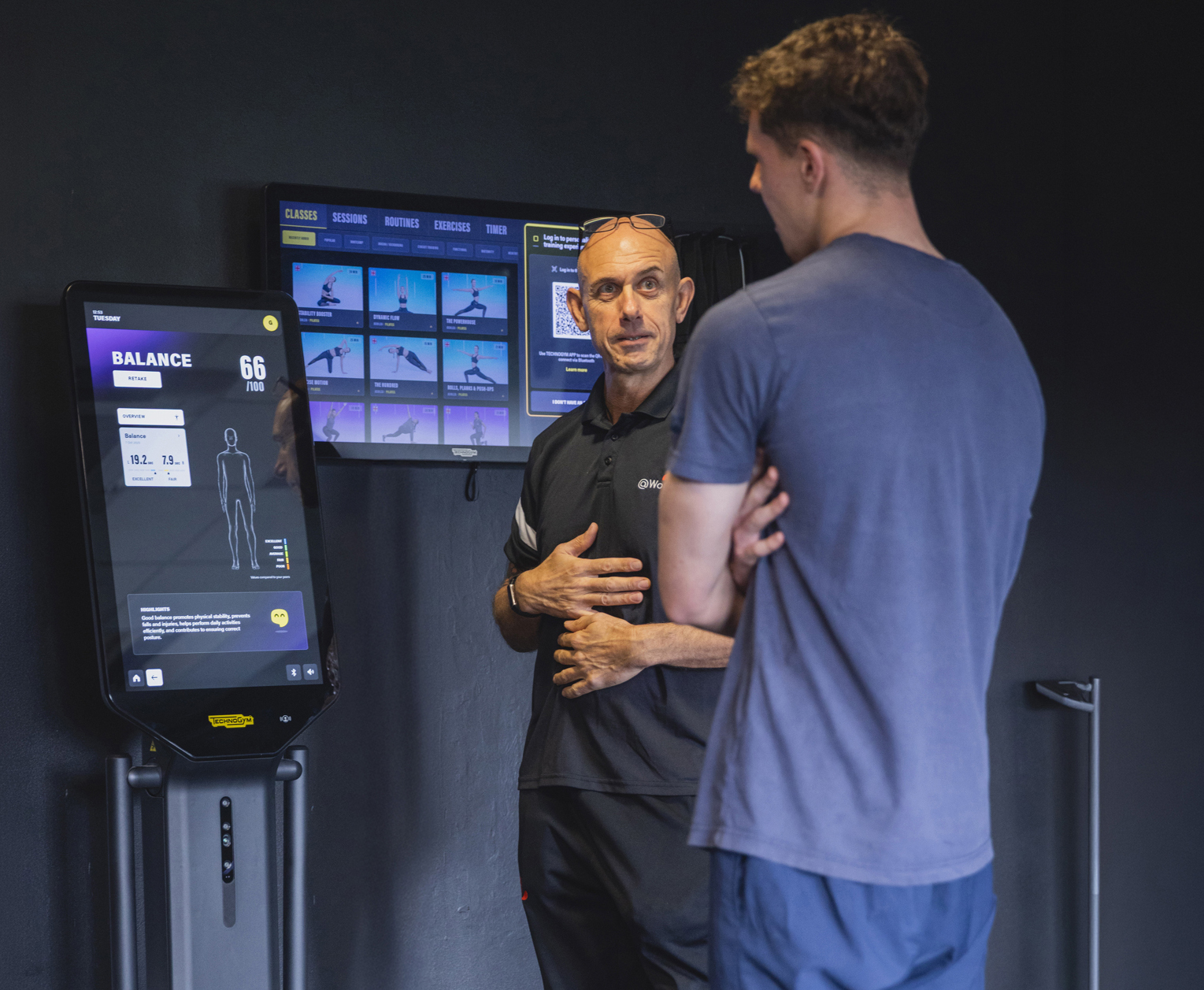 Male instructor and gym member with Techogym device
