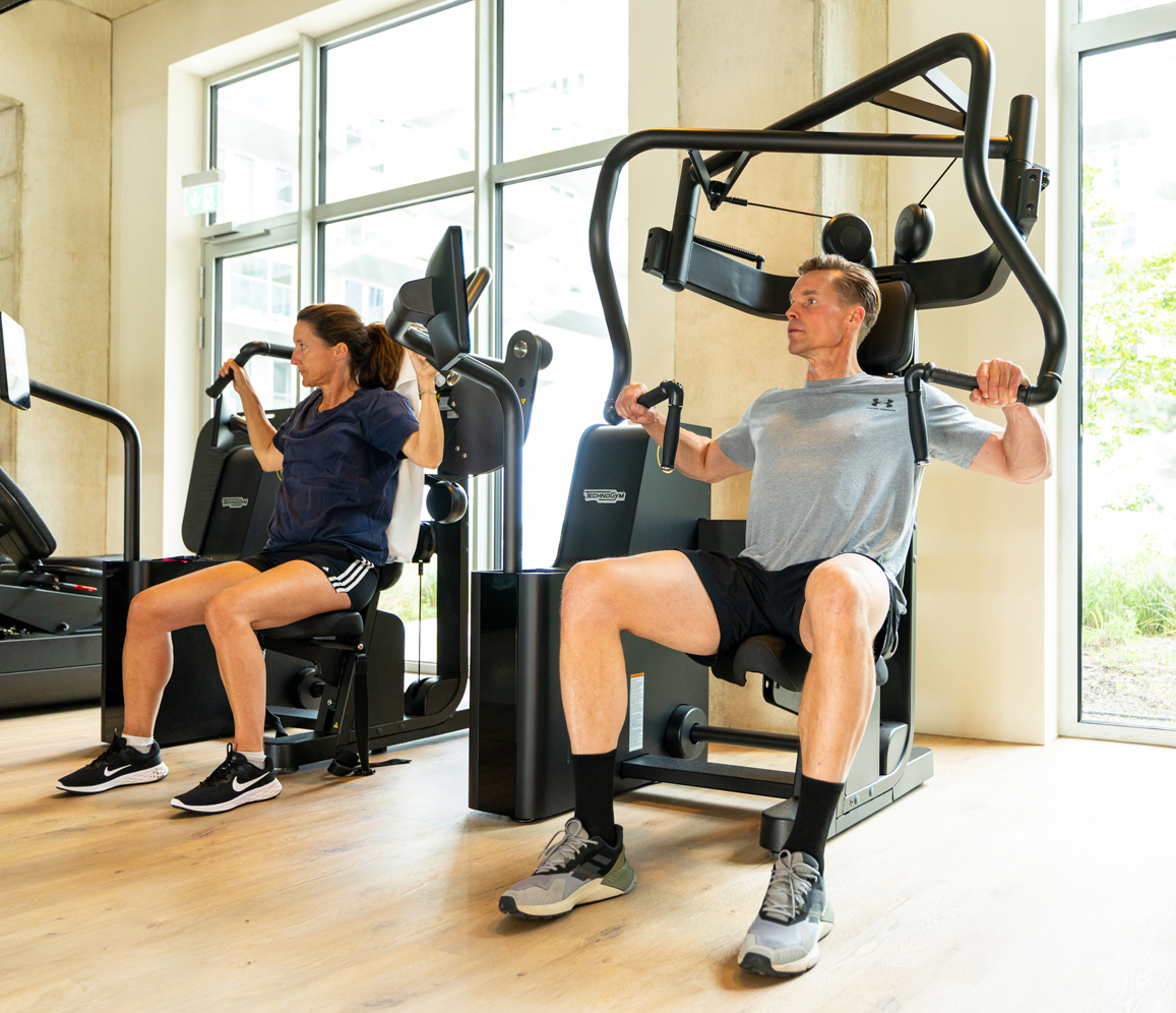 Man in foreground and woman in background using Technogym Biocircuit equipment in gym