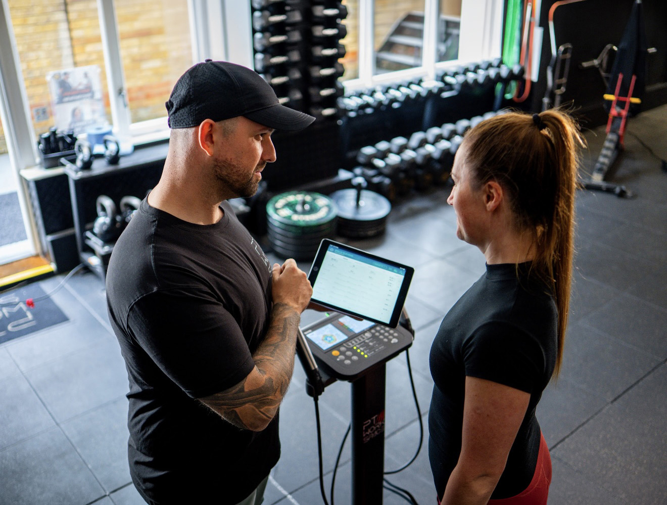 Instructor and member on gym floor with Tanita device
