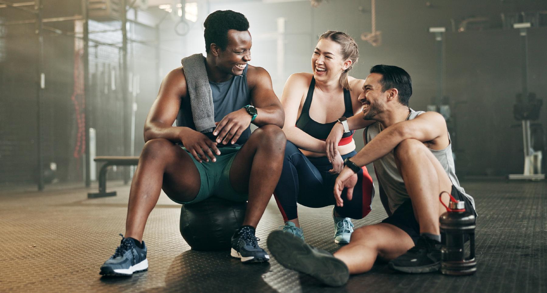 two men and one woman laughing on gym floor
