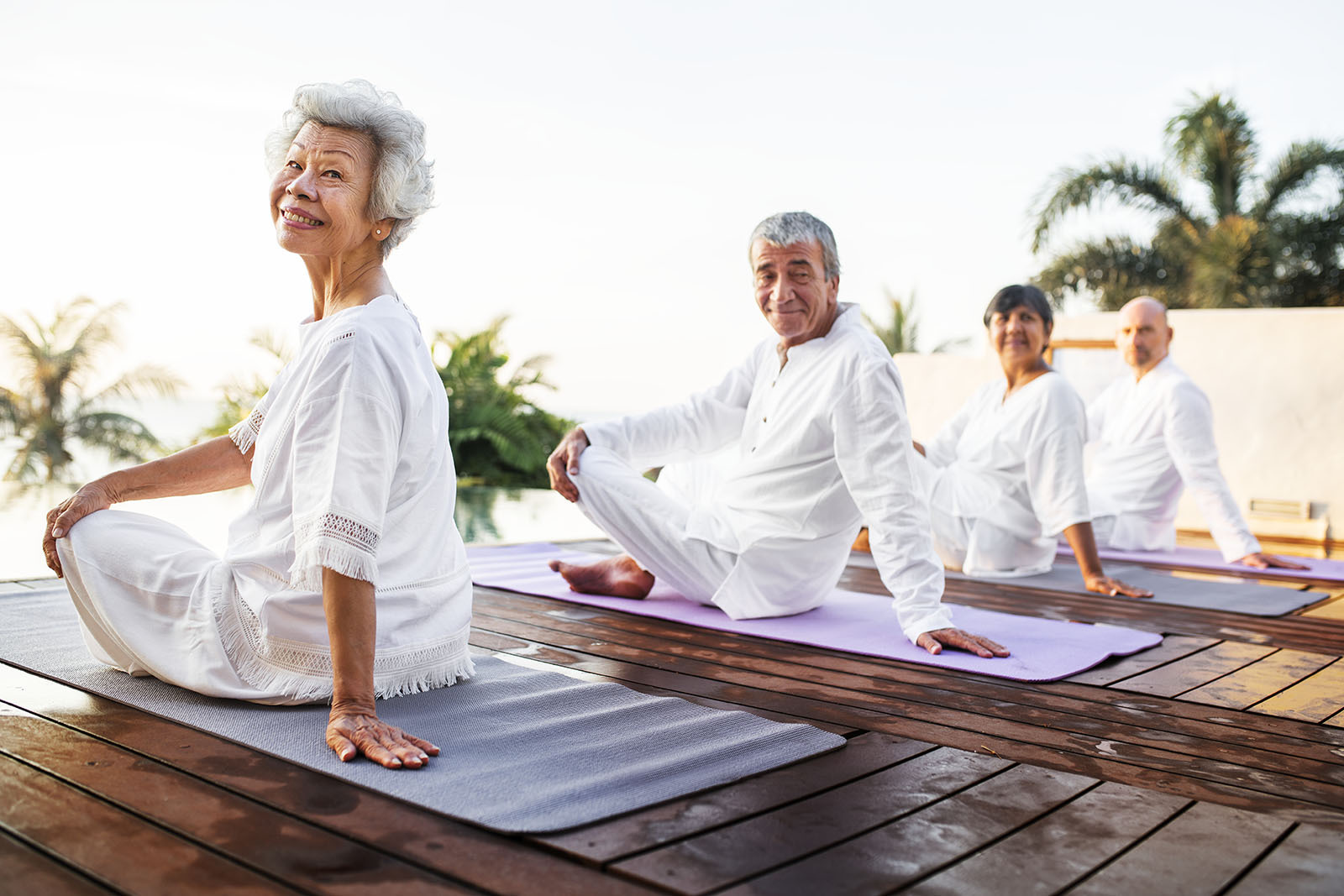 Older people on yoga mats looking back towards camera
