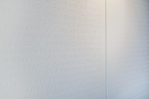 The lyrics to ‘Give Peace a Chance’ are inscribed repeatedly on the walls in the style of a war memorial. / Fairmont Le Reine Elizabeth