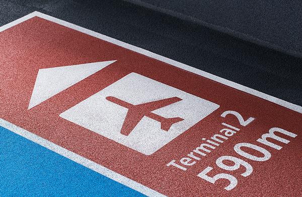  The running tracks in the airport are colour coded: red for arrivals and blue for departures. White stenciled symbols direct passengers to the correct part of the building