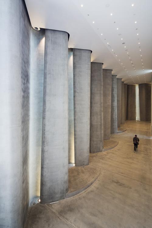 Gaps between the exterior facade allow controlled amounts of light through at various points in the day, creating an interior colonnade effect / Patterson Associates