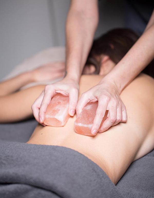 Warm salt stones massage the body before an exfoliation