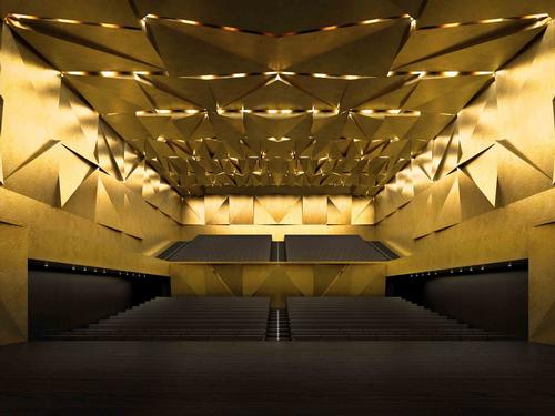 The auditorium interiors are golden with faceted panels / Simon Menges