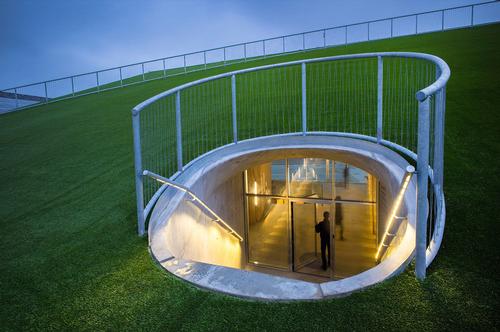 The entrance to the building from the green carpet adjacent to the football fields / Jens Lindhe / BIG