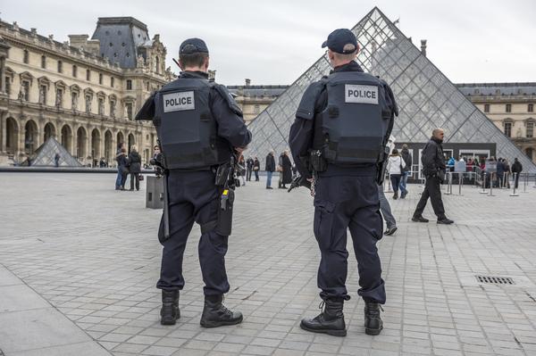Police officers stand near the Louvre, Paris