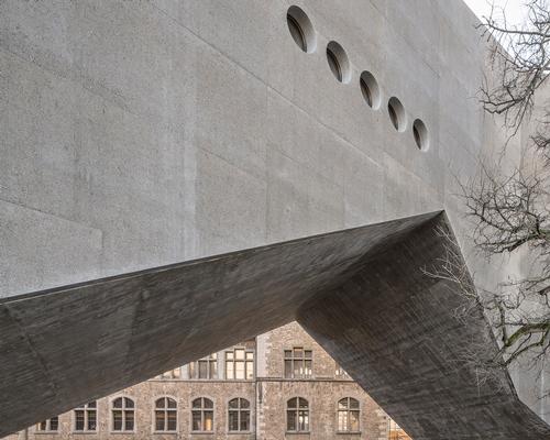 The extension is a minimalist concrete volume that connects to the old 19th century building / Roman Keller