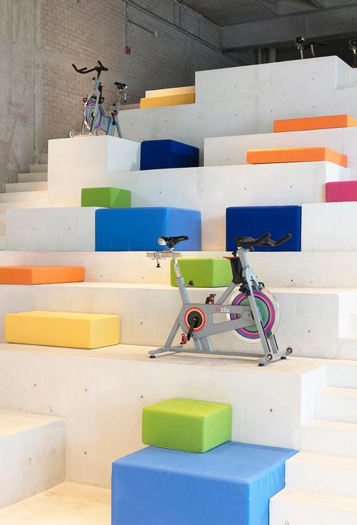 The steps of the monolith are covered with multicoloured poly-chromatic cushions and a small number of gym bikes / Jaime Navarro Soto