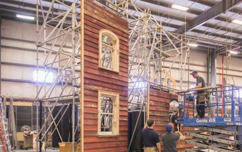 The house is formed of two facades propped up from behind by scaffolding, using materials sourced from a traditional red American barn / The Metropolitan Museum of Art