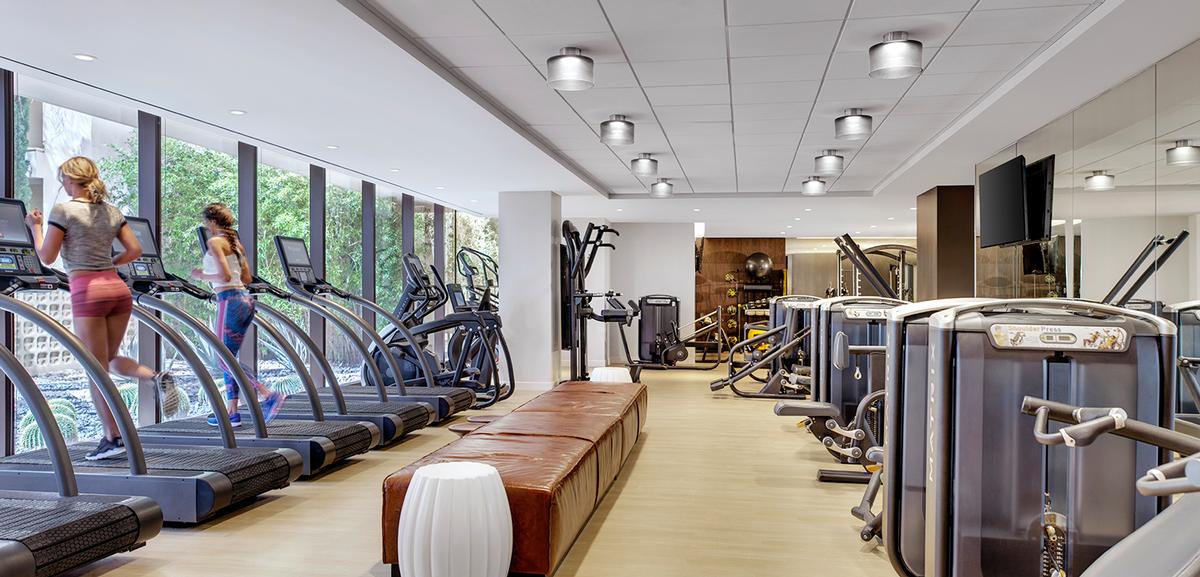 The gym features a comprehensive fitness area with Woodway treadmills and Matrix fitness equipment