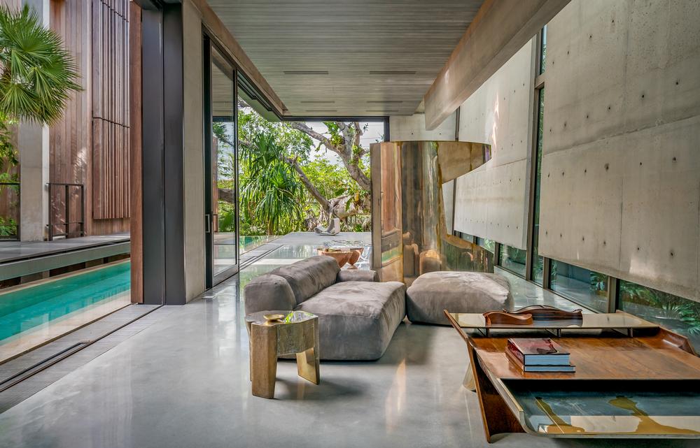 Floor to ceiling windows let in natural light and offer views of the vegetation. The pool provides a sense of coolness