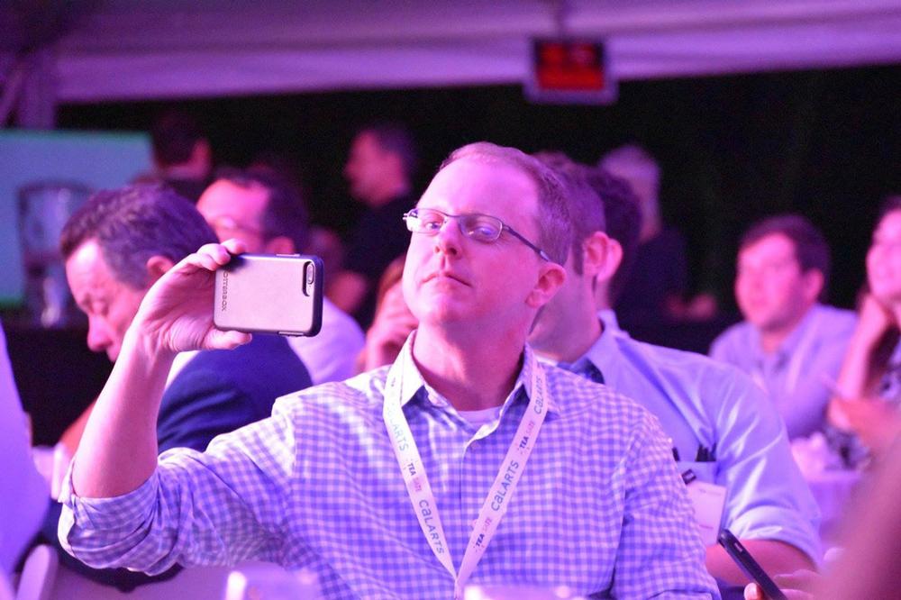 A conference attendee takes a picture at SATE (Storytelling + Architecture + Technology = Experience)