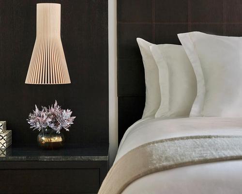 Rooms feature custom-made beds framed by dark leather headboards and paneling, paired with pale floors of locally-sourced hardwood