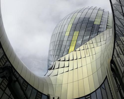 the building's wooden skeleton is covered by two layers of silk-screen printed glass panels, photovoltaic sections and perforated lacquered aluminium panels / XTU