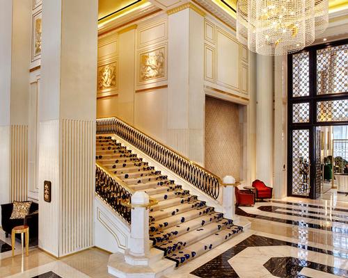 The hotel’s lobby features soaring ceilings and a grand staircase lit by a crystal chandelier