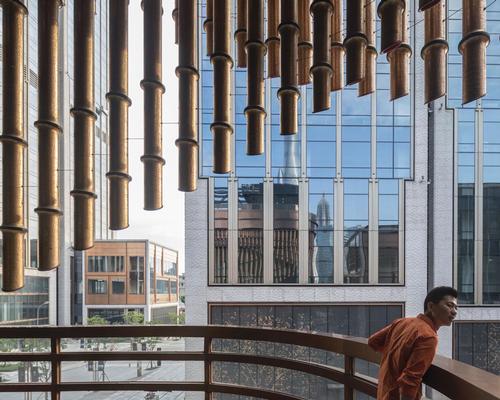 Overlapping layers of bronze tubes form the building's moving curtain / Laurian Ghinitoiu