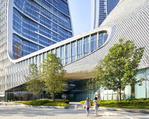 The two streamlined towers, clad in a scale-like skin of aluminium tiles, are set atop a 116,000sq m six-storey podium / Hufton + Crow