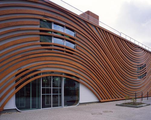 The building’s external walls are clad with swirling wooden slats that recall the circular movements on the surface of water and reference to the circulation of energy and flows / Hélène Binet