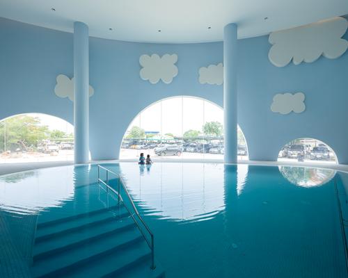 There is a swimming pool with artificial clouds floating above it / Ketsiree Wongwan