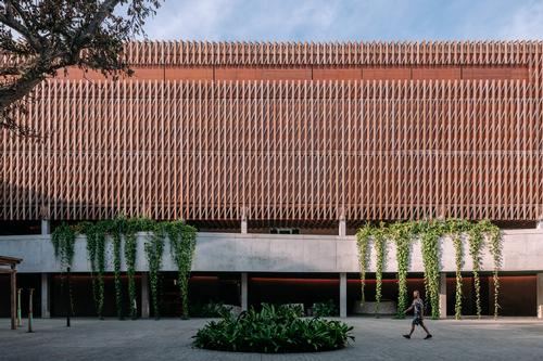 The building has a square layout and is constructed from a mix of open brickwork and timber cladding / Kevin Mak