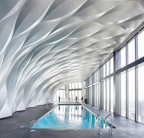 A double-height aquatics centre features an infinity pool / Hufton+Crow