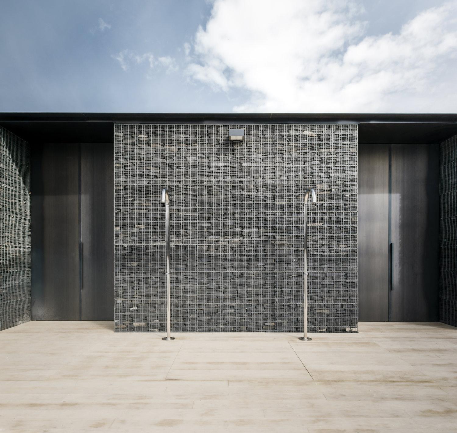 An example of the dark limestone walls behind poolside showers / gh3 architecture