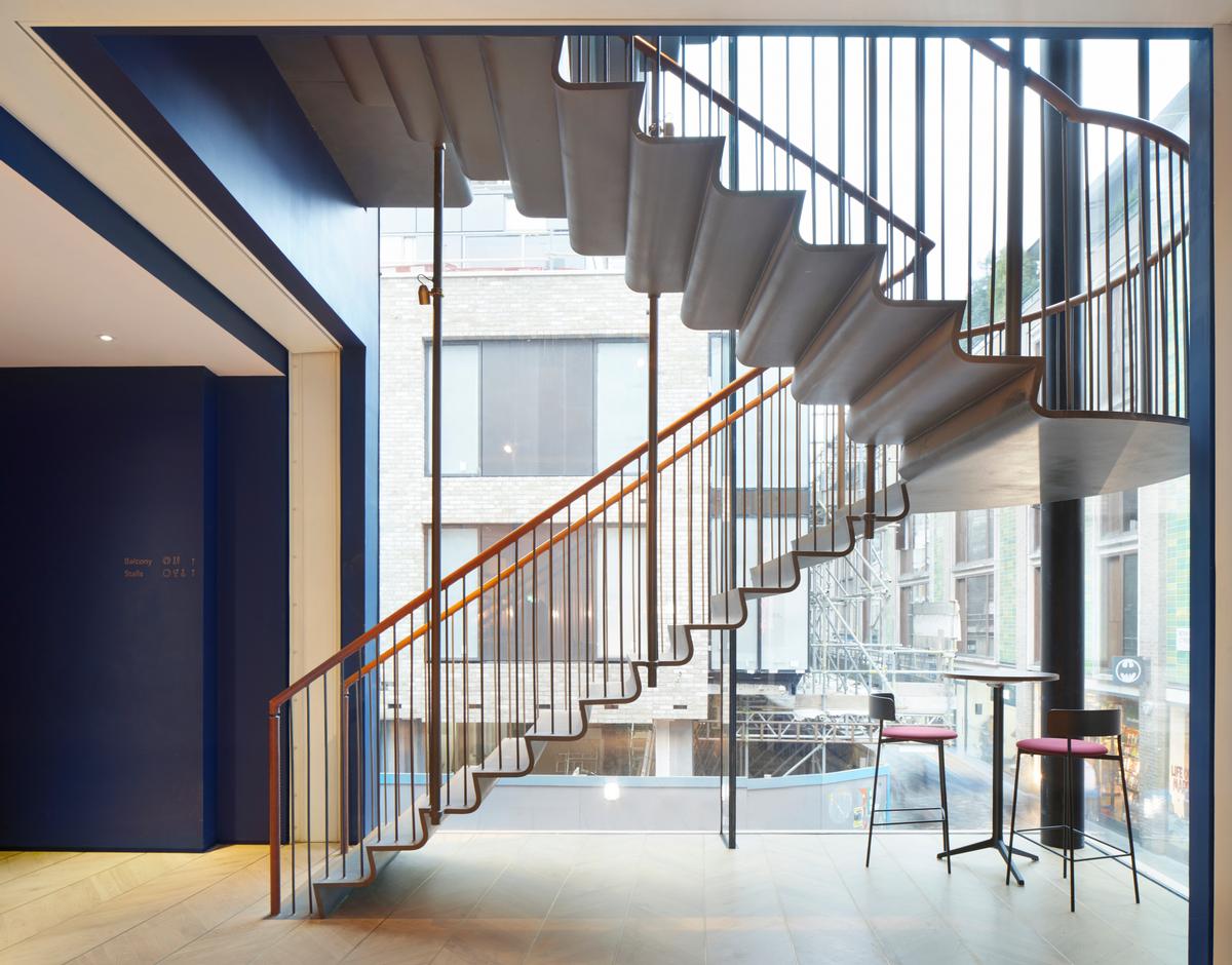 A rolled-steel feature staircase hangs in the glazed corner of one of the buildings / SODA Studio