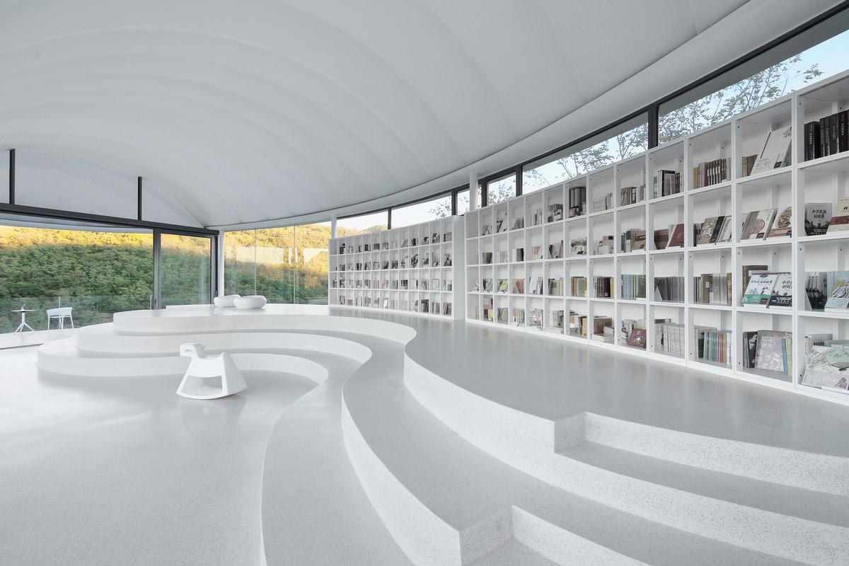 While bookshelves and tiered seating are integrated into the structure, following its curves / Jin Xiaowen